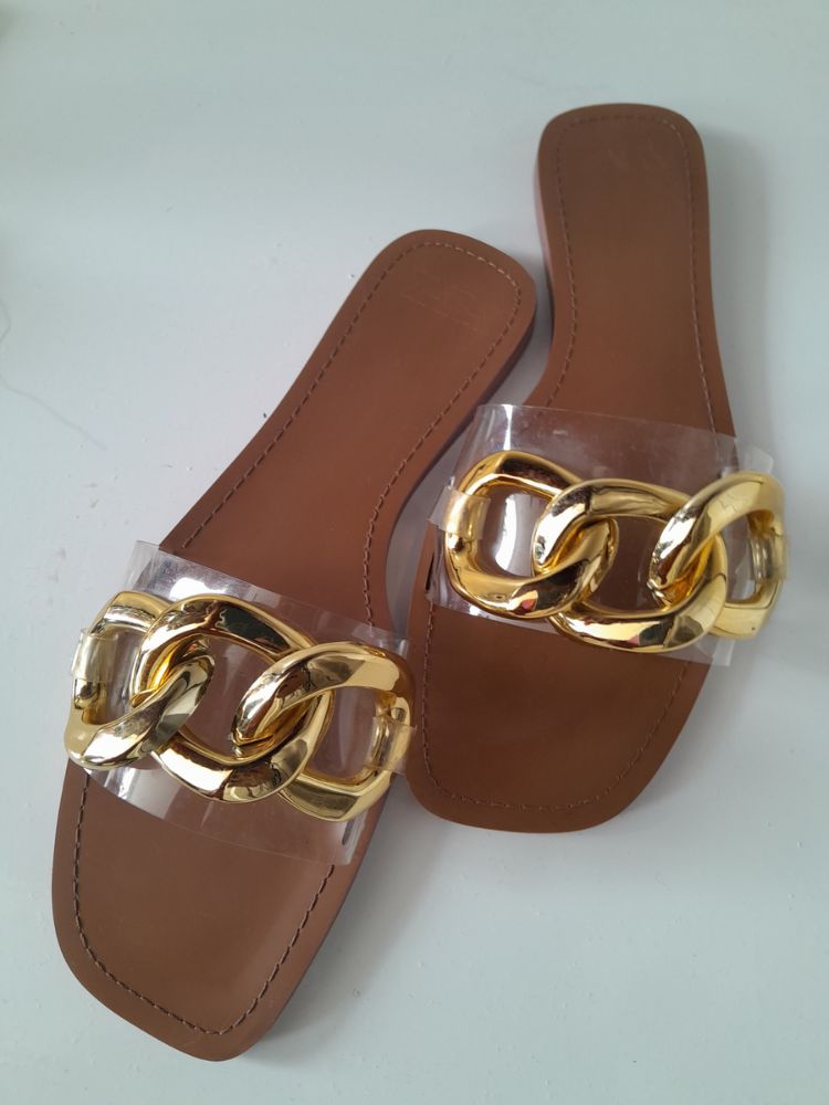  Clear strapped brown based sandals with a braided golden design at the top. 
